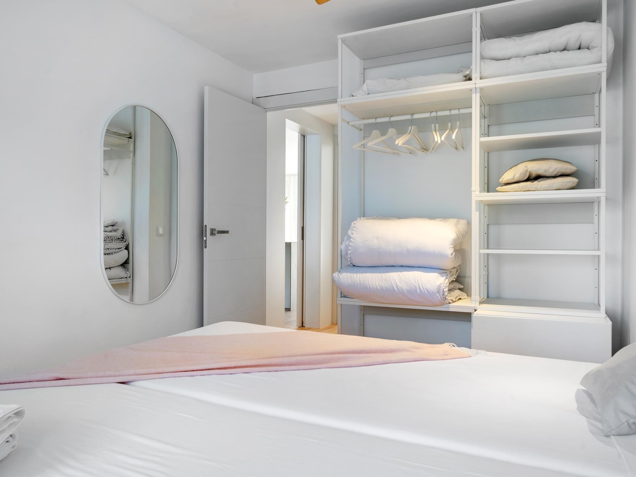 Une chambre à coucher moderne avec un lit, une armoire avec espace pour suspendre les vêtements et un miroir.