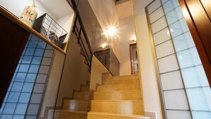 Un escalier avec une rampe, un luminaire au-dessus et une bouteille posée sur une étagère.