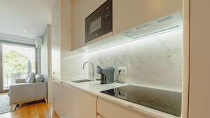 A modern kitchen with a built-in microwave, a coffee machine, and a large window. - Legacy Oporto Premium Apartment C by Vacationy (Porto)