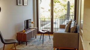 A modern living room with a sofa, a coffee table, a TV, and a small side table. - Legacy Oporto Premium Apartment C by Vacationy (Porto)