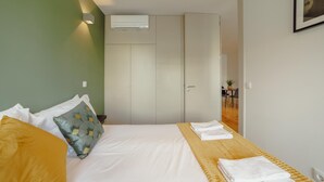 A hotel room with a bed, a bedside table, a wardrobe, and a small dining area. - Legacy Oporto Premium Apartment C by Vacationy (Porto)