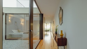 A modern interior with a wooden floor, a glass door leading to a balcony, and a small table with a vase. - Legacy Oporto Premium Apartment B by Vacationy (Porto)