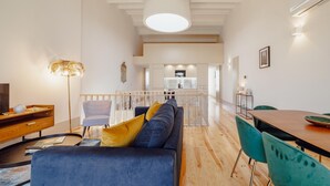 A modern living room with a sofa, a dining table, and a staircase leading to an upper level. - Legacy Oporto Premium Apartment I by Vacationy (Porto)
