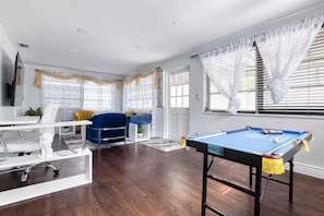 Relax in this stylish living room with a pool table, sofa, coffee table, and TV.