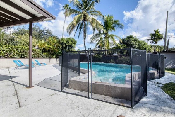 Relax by the pool surrounded by lush greenery and palm trees.
