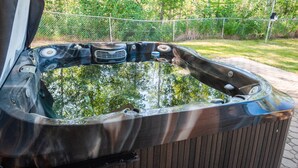 Un jacuzzi con muelle de madera y una cerca de malla metálica al fondo.