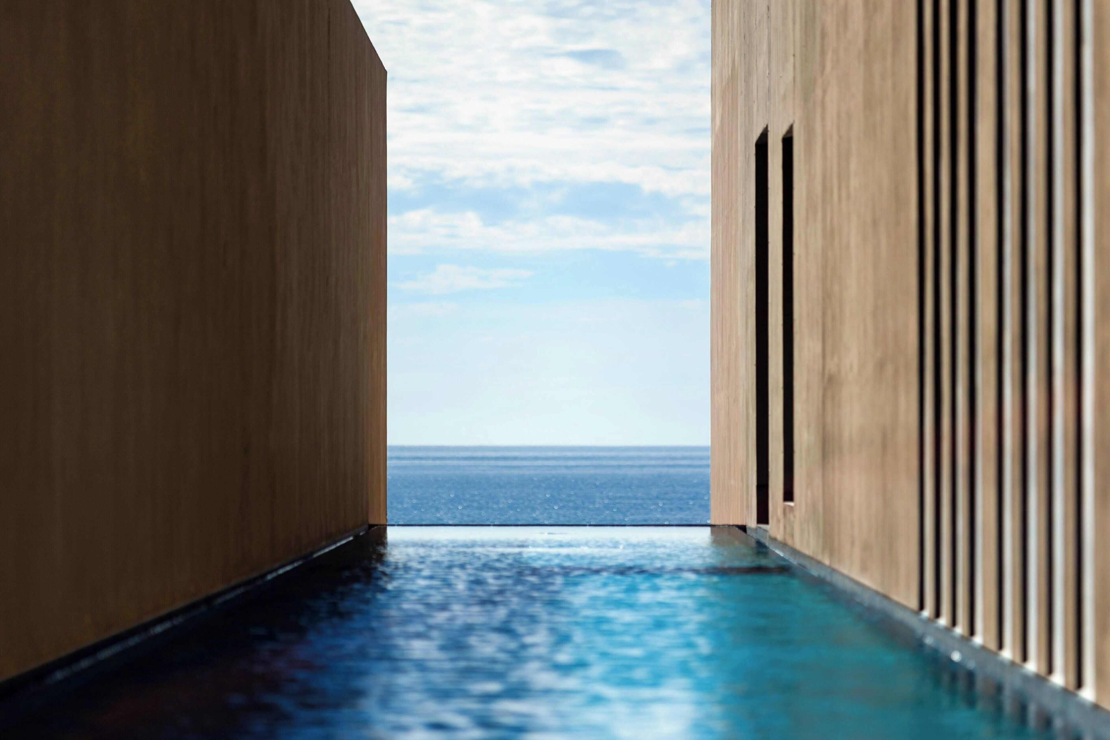 Pasillo que conduce a una piscina con vistas al mar.