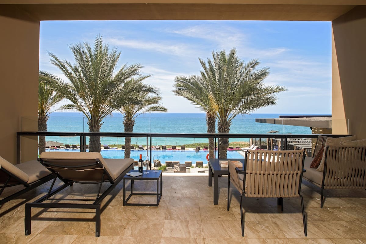 Un balcon avec vue sur la piscine, des chaises longues et une table.