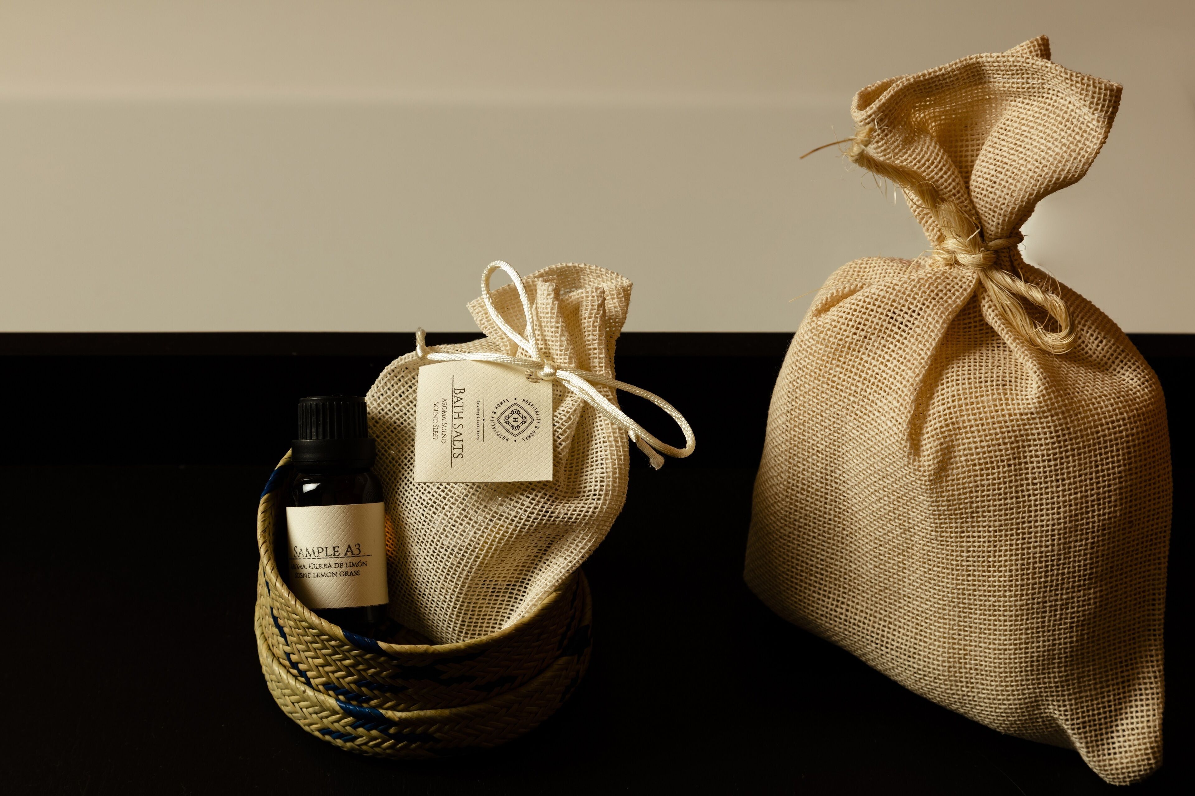 Una botella de vino Sample A3 y un saco de arpillera con una etiqueta, sobre una superficie oscura.