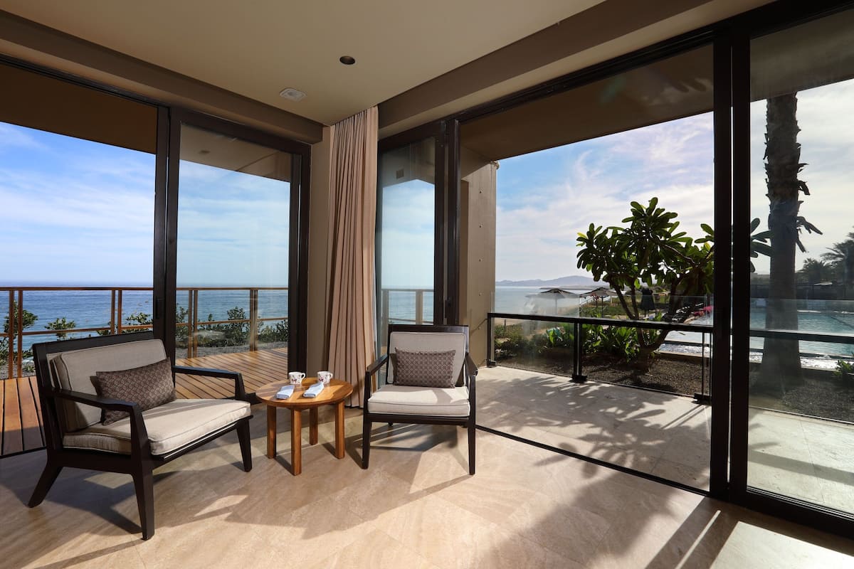 Un balcon avec deux chaises, une petite table et une vue sur la mer.