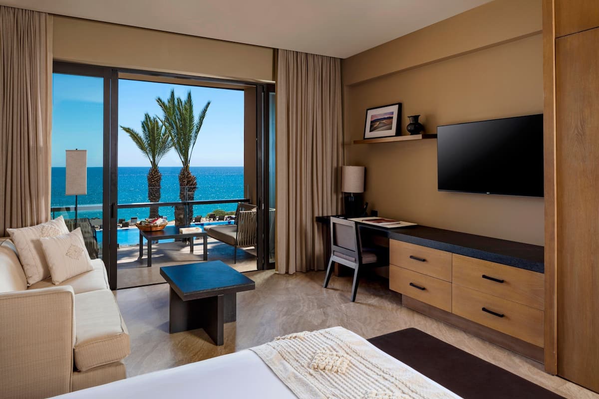 Une chambre d’hôtel avec un balcon, un lit, un bureau et une télévision.