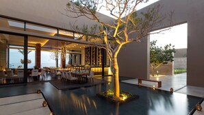 A modern indoor dining area with a central water feature, seating, and a bar. - Casa Maat At JW Marriott Los Cabos Beach Resort & Spa (San José del Cabo)