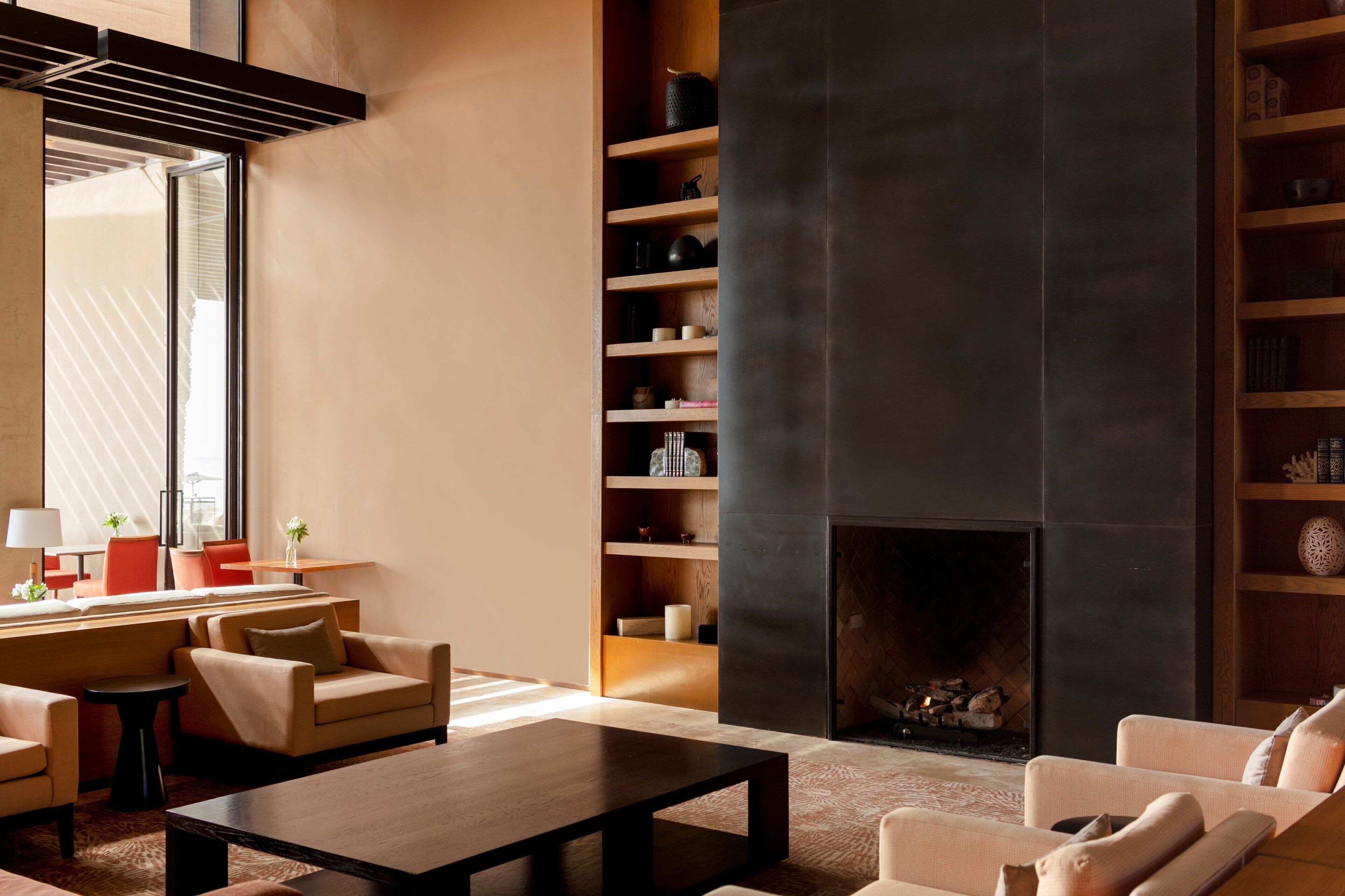 A modern living room with a fireplace, comfortable seating, and a bookshelf.