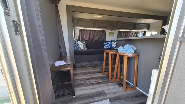 A compact RV interior with a kitchenette, a seating area with a couch, and a small table. - The Air Bee-N-Bee: In The Heart of the Black Hills (Custer)