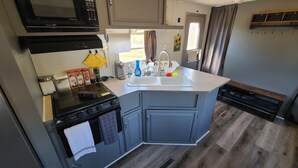A compact kitchen with a microwave, stove, sink, and cabinets. - The Air Bee-N-Bee: In The Heart of the Black Hills (Custer)