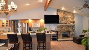 A spacious kitchen with a stone fireplace, wooden bar stools, and a flat-screen TV mounted above the counter. - BICKING & Fishing, National Parks .Water park. Shooting. Gamblingnd. IPA at PA.  (Clifton)