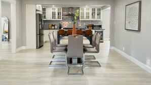 A modern kitchen with white cabinets, a central island, and a dining area with a glass table and metal chairs. - modERn Luxury Home🌇🎆🌉Limited time offer! (Walnut Creek)