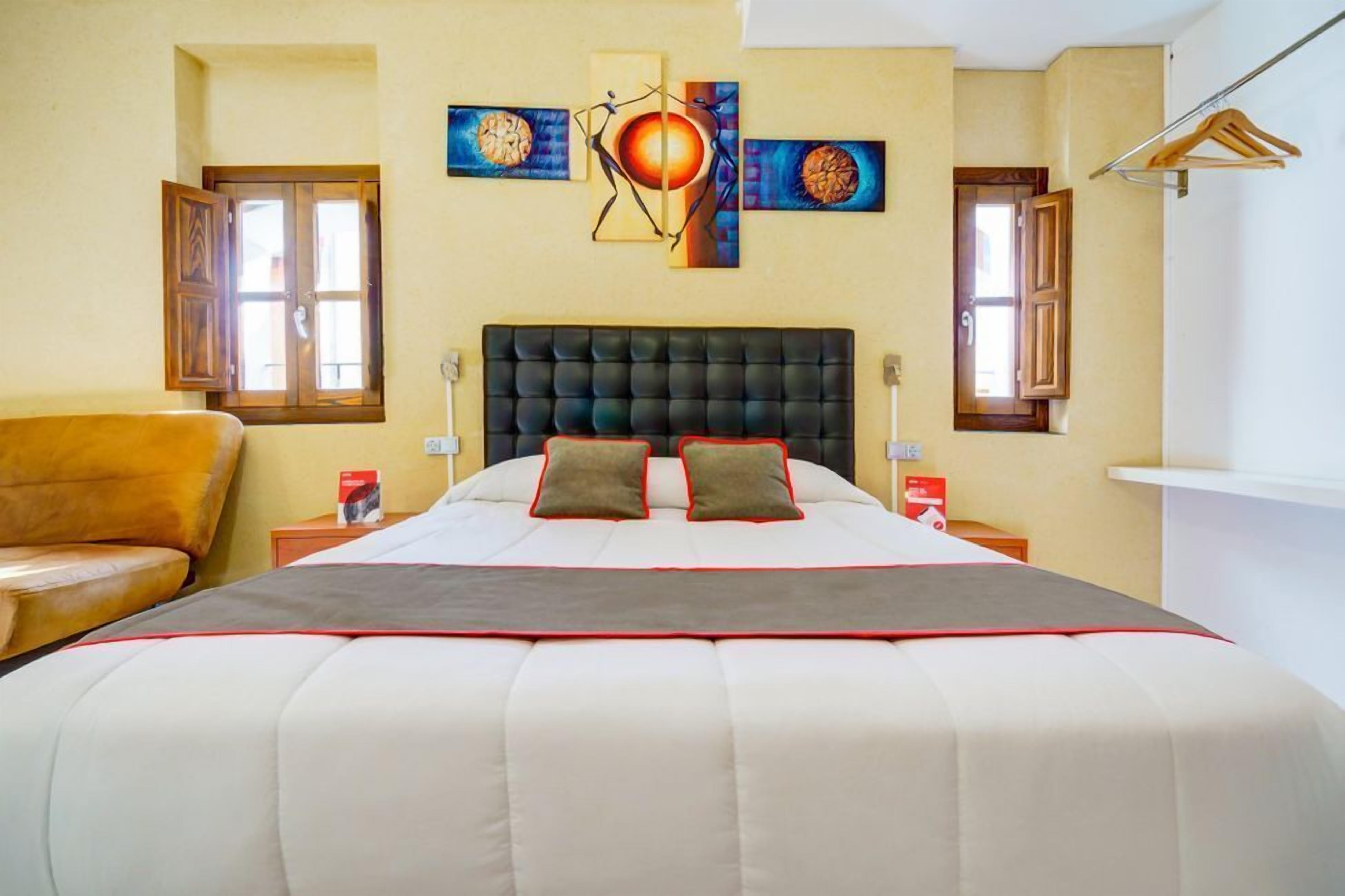 Ein Schlafzimmer mit einem großen Bett, zwei Nachttischen, einem Holzstuhl und Bildern an der Wand.