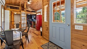 Interior d'una cabana de fusta amb menjador, cuina i una finestra gran.