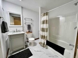 Bañera con ducha, secador de pelo, toallas, shampoo