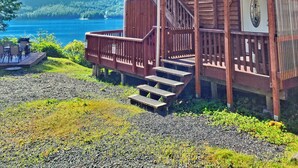 A wooden cabin with a deck, a staircase, and a view of a lake and mountains. - Private 2 bedroom Oceanfront Oasis with Panoramic views! (Craig)