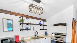 A modern kitchen with white cabinets, a stainless steel oven, and a wooden floor. - Private 2 bedroom Oceanfront Oasis with Panoramic views! (Craig)