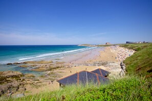 A coastal beach with rocky areas, a sandy beach, and a grassy hill. - 5 Ocean Gate, Newquay - a prime position apartment near Fistral Beach (Newquay)