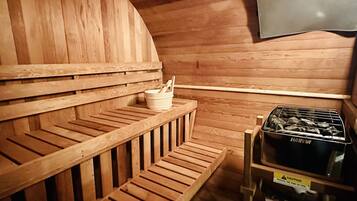 A sauna with wooden benches, a small table with a bowl and spoon, and a caution sign.
