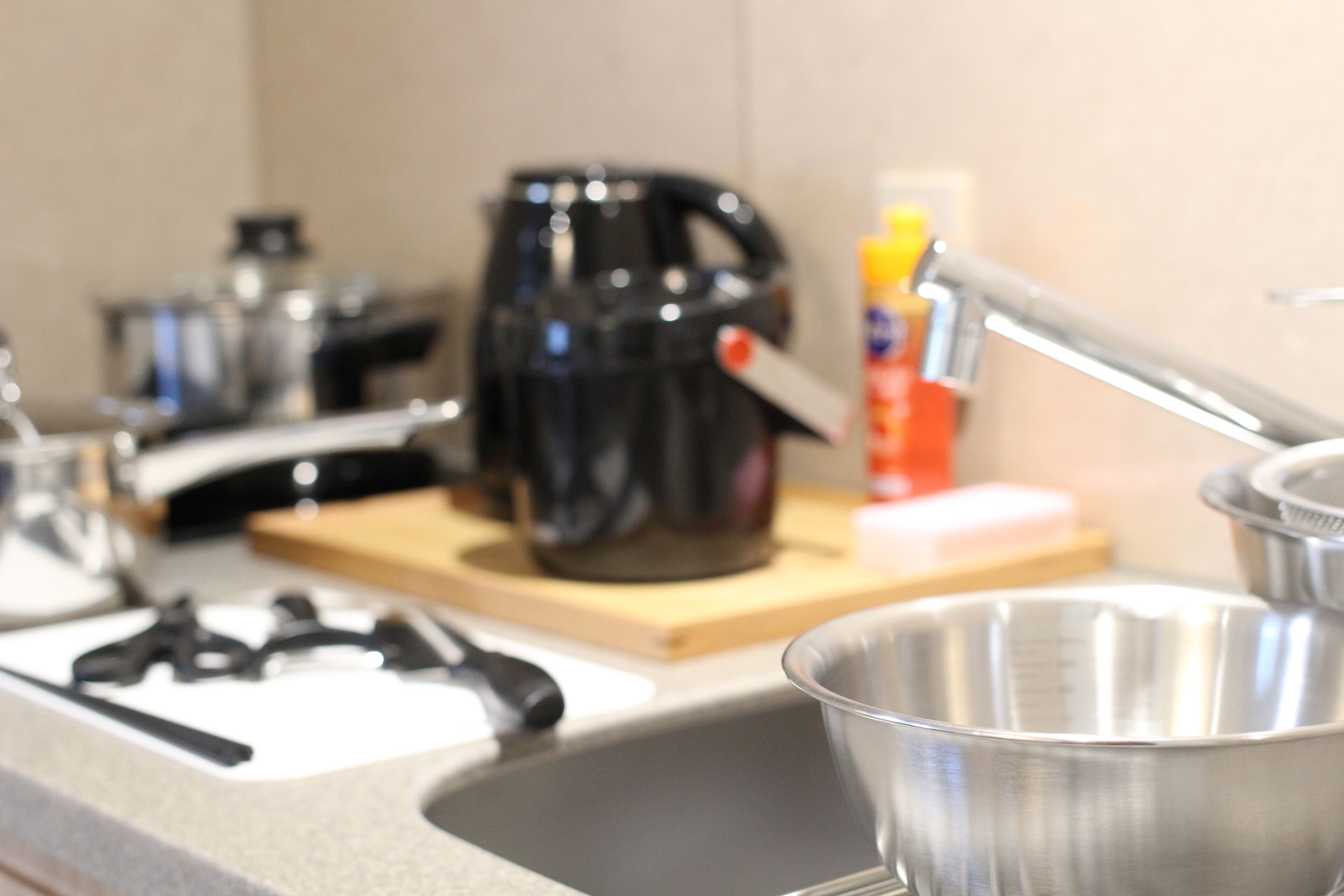 A kitchen with a coffee maker, a sink, and a metal bowl.