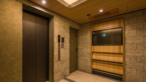 Un ascensor con pantalla digital, pared de paneles de madera y suelo de baldosas.