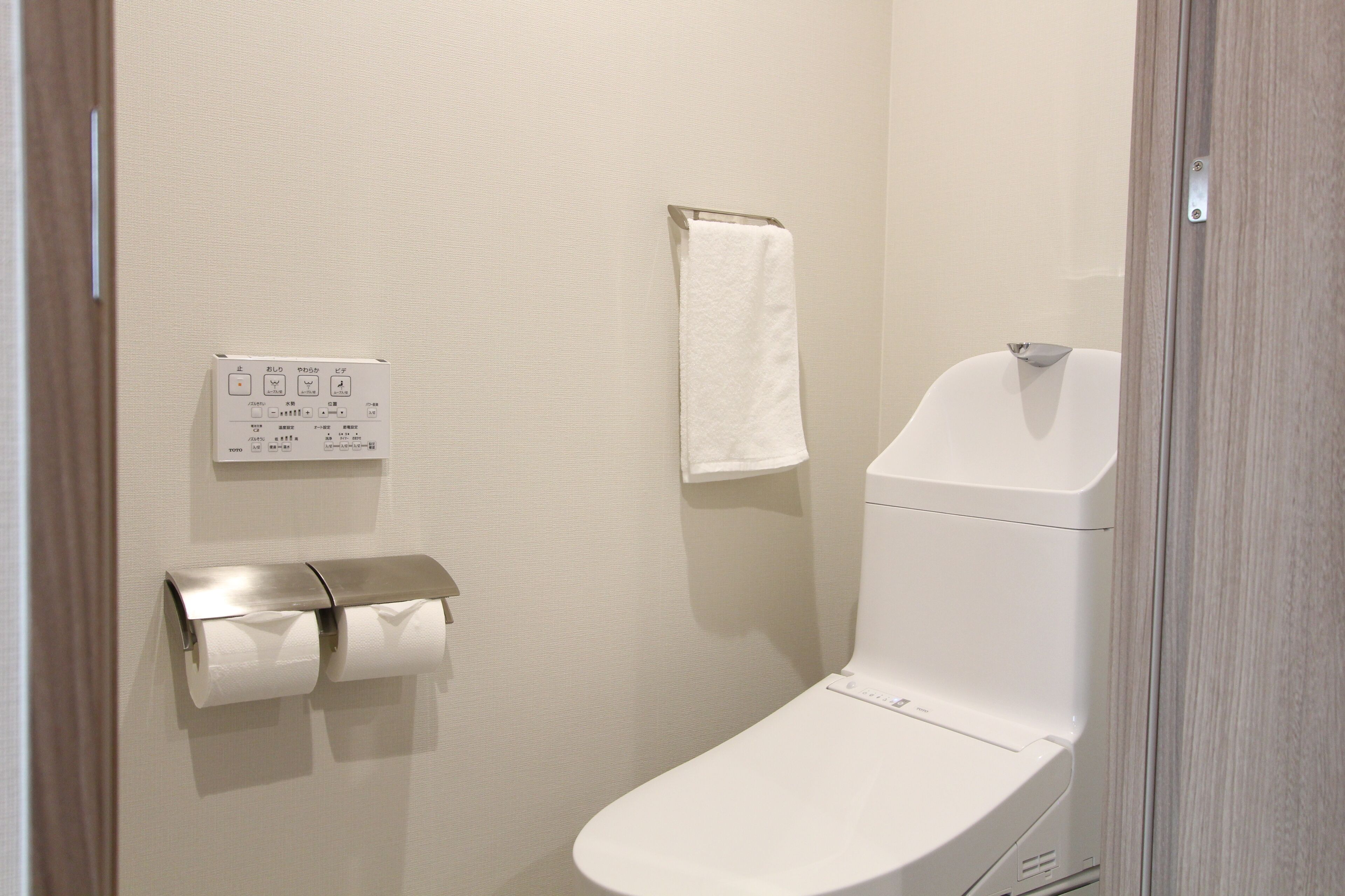 A bathroom with a toilet, a towel rack, and a paper towel dispenser.