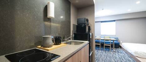 A compact kitchen with an induction cooktop, a coffee maker, and a microwave.
