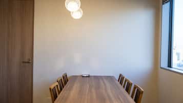 A conference room with a wooden table, chairs, a hanging light fixture, and a window with a view.