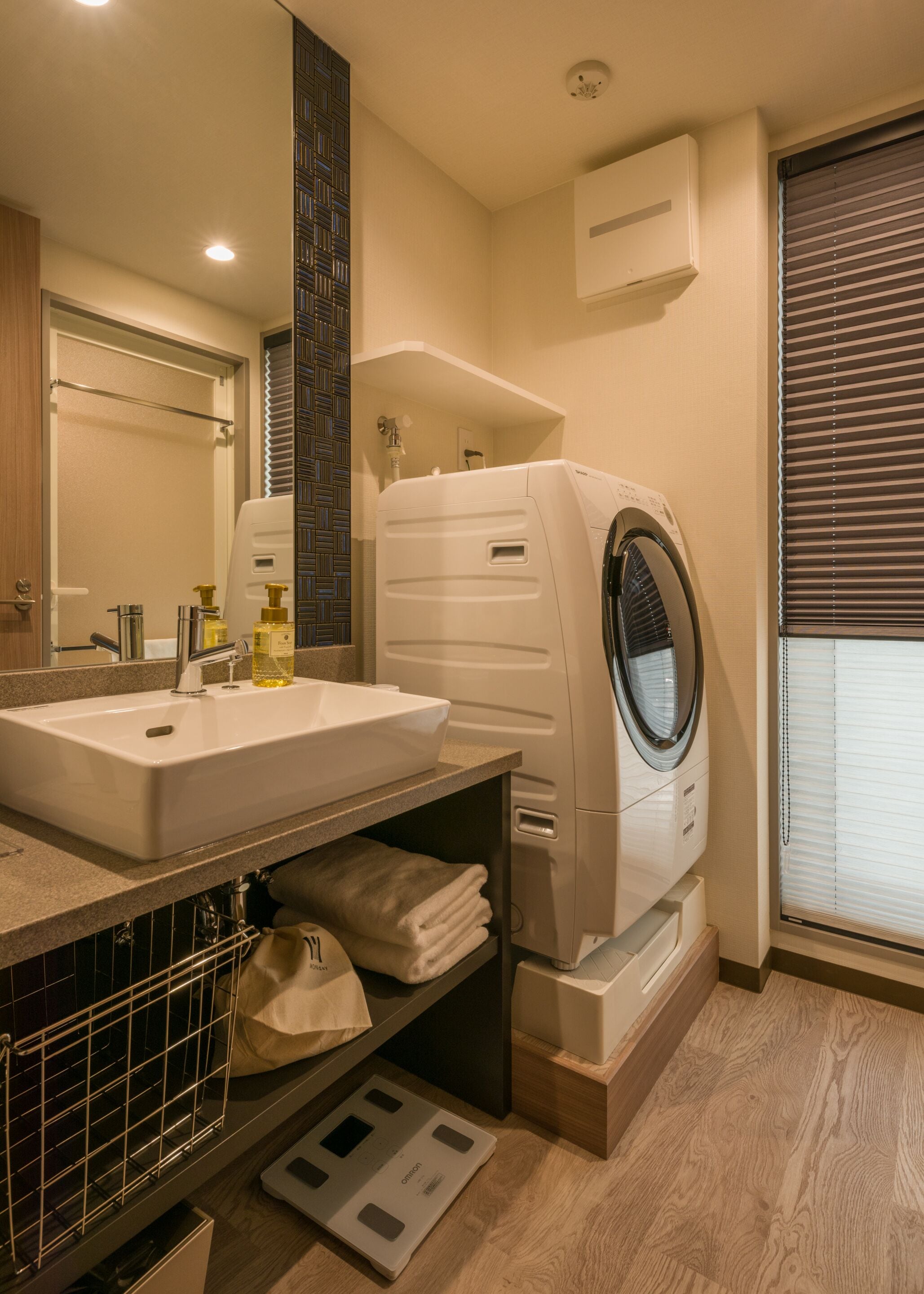 A modern bathroom with a built-in sink, a washing machine, and a mirror.