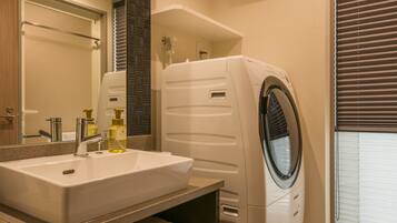 A modern bathroom with a built-in sink, a washing machine, and a mirror.
