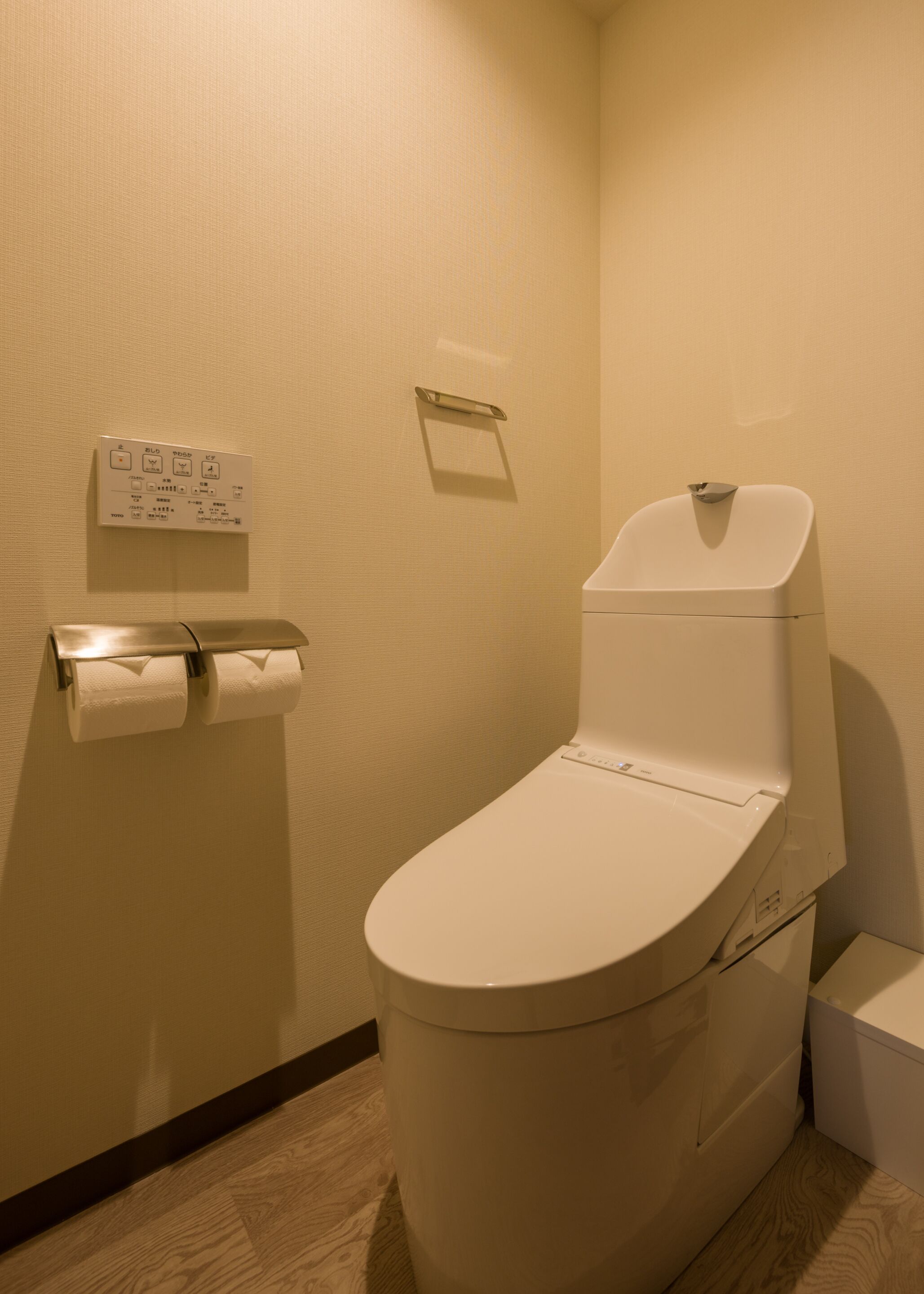 A standard hotel bathroom with a toilet, a hand dryer, and a paper towel dispenser.