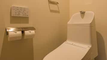 A standard hotel bathroom with a toilet, a hand dryer, and a paper towel dispenser.