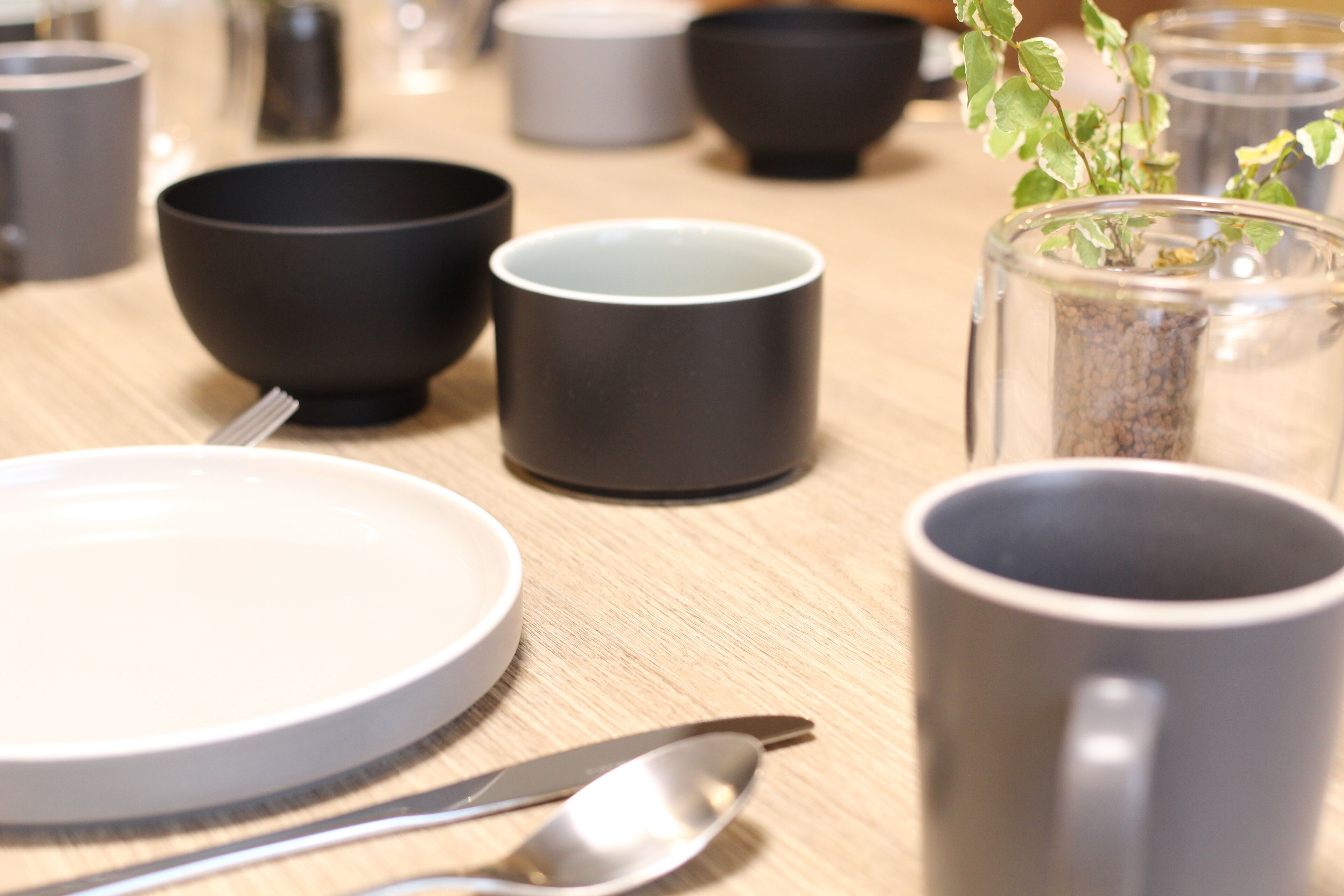 A dining table with various bowls, a plate, a spoon, and a mug.