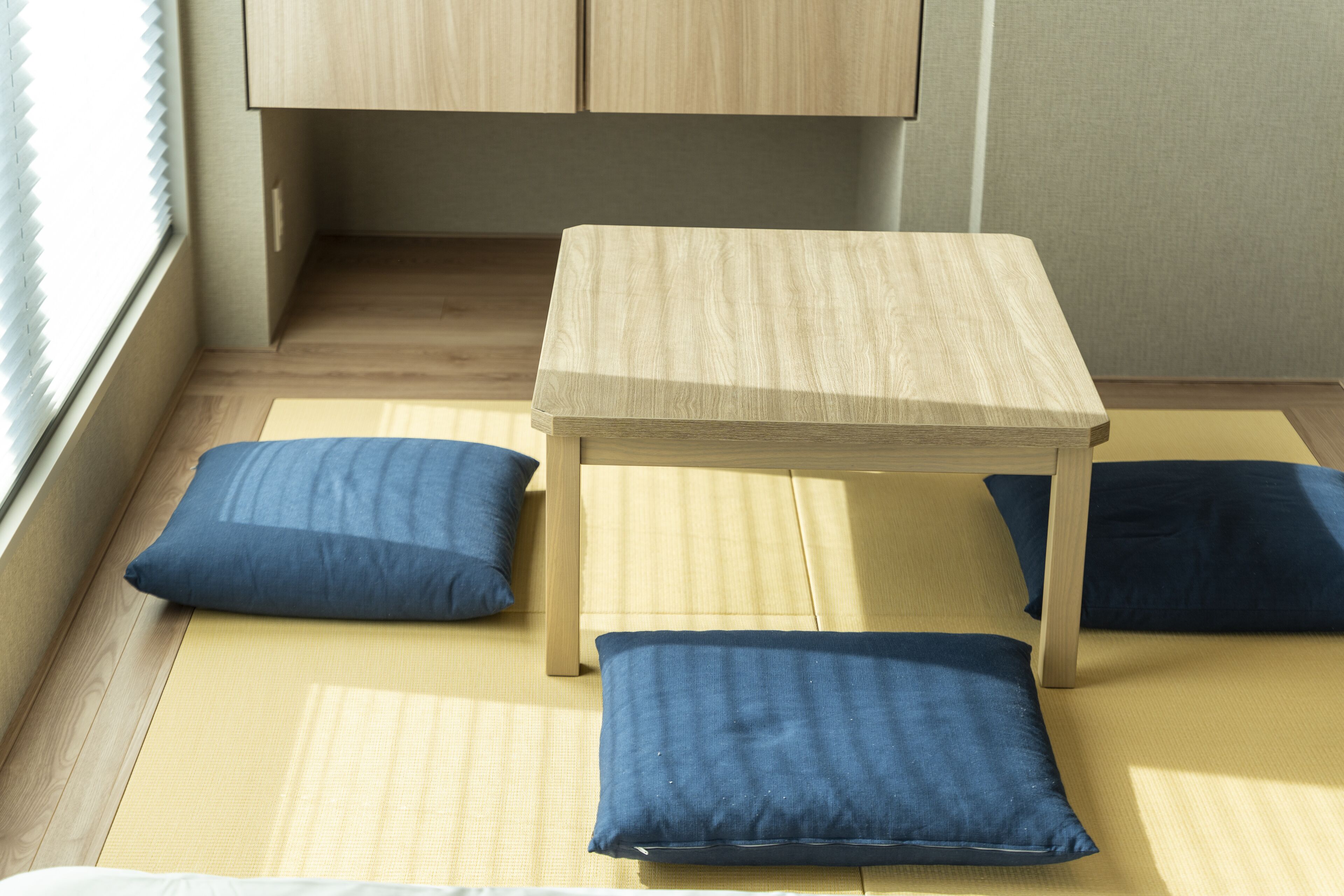 A room with tatami mats, a wooden table, and blue cushions.