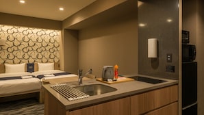 Habitación de hotel moderna con tocador de madera, lavamanos y microondas.