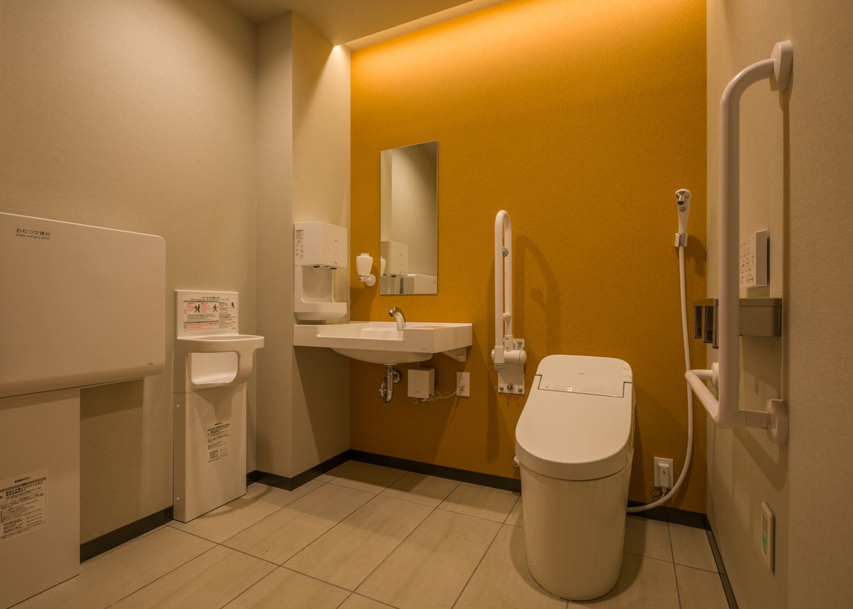 Une salle de bain moderne équipée de toilettes, d’un lavabo et d’un sèche-mains.