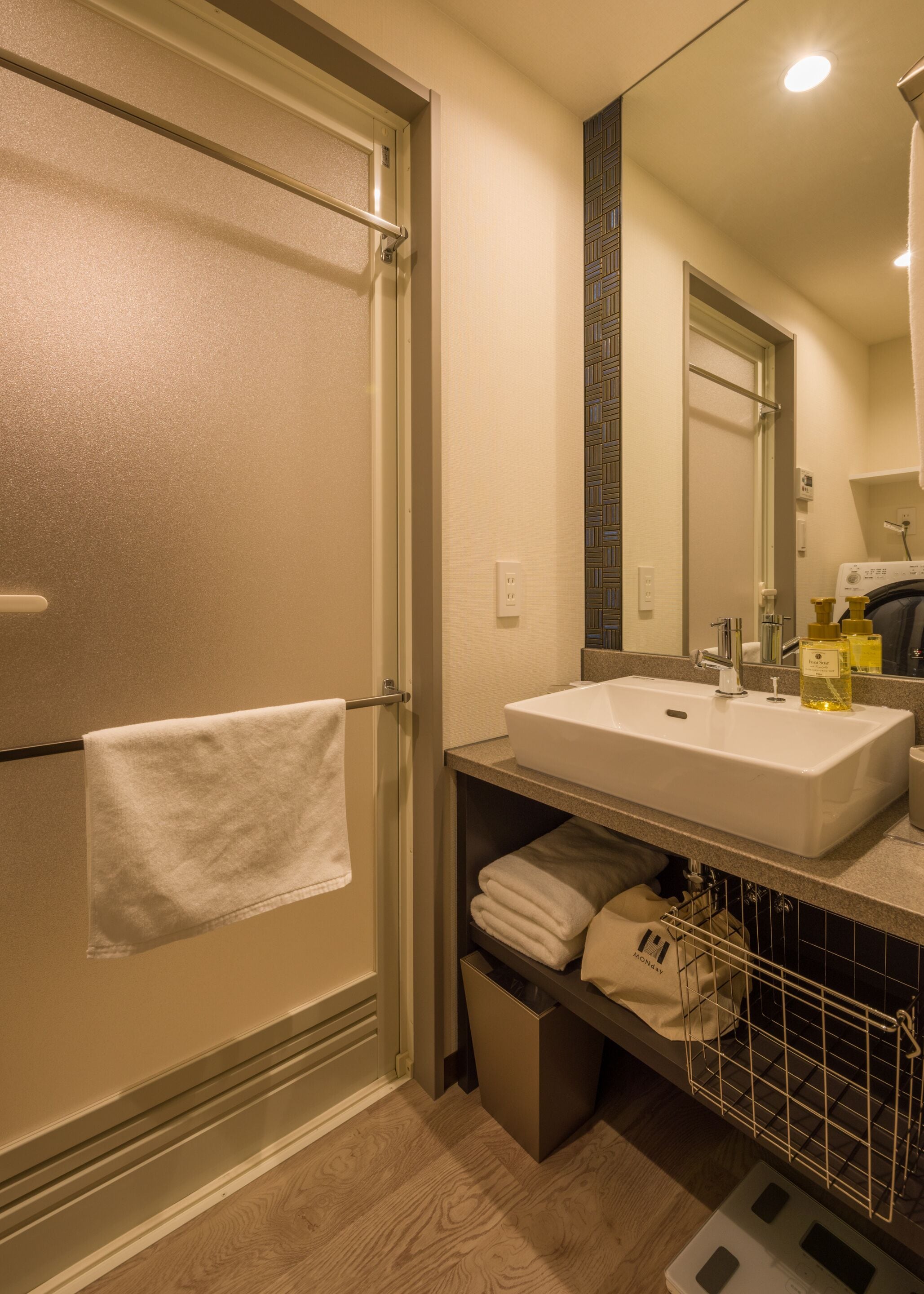 A bathroom with a shower, a sink, and a towel rack.
