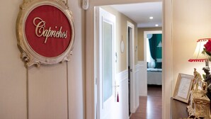 Um corredor com uma placa emoldurada com a inscrição 'Cabrichos', uma porta e uma estátua sobre uma mesa.