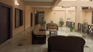 A hotel lobby with a long corridor, sofas, a coffee table, and potted plants. - Hotel Centre Point (Tinsukia)