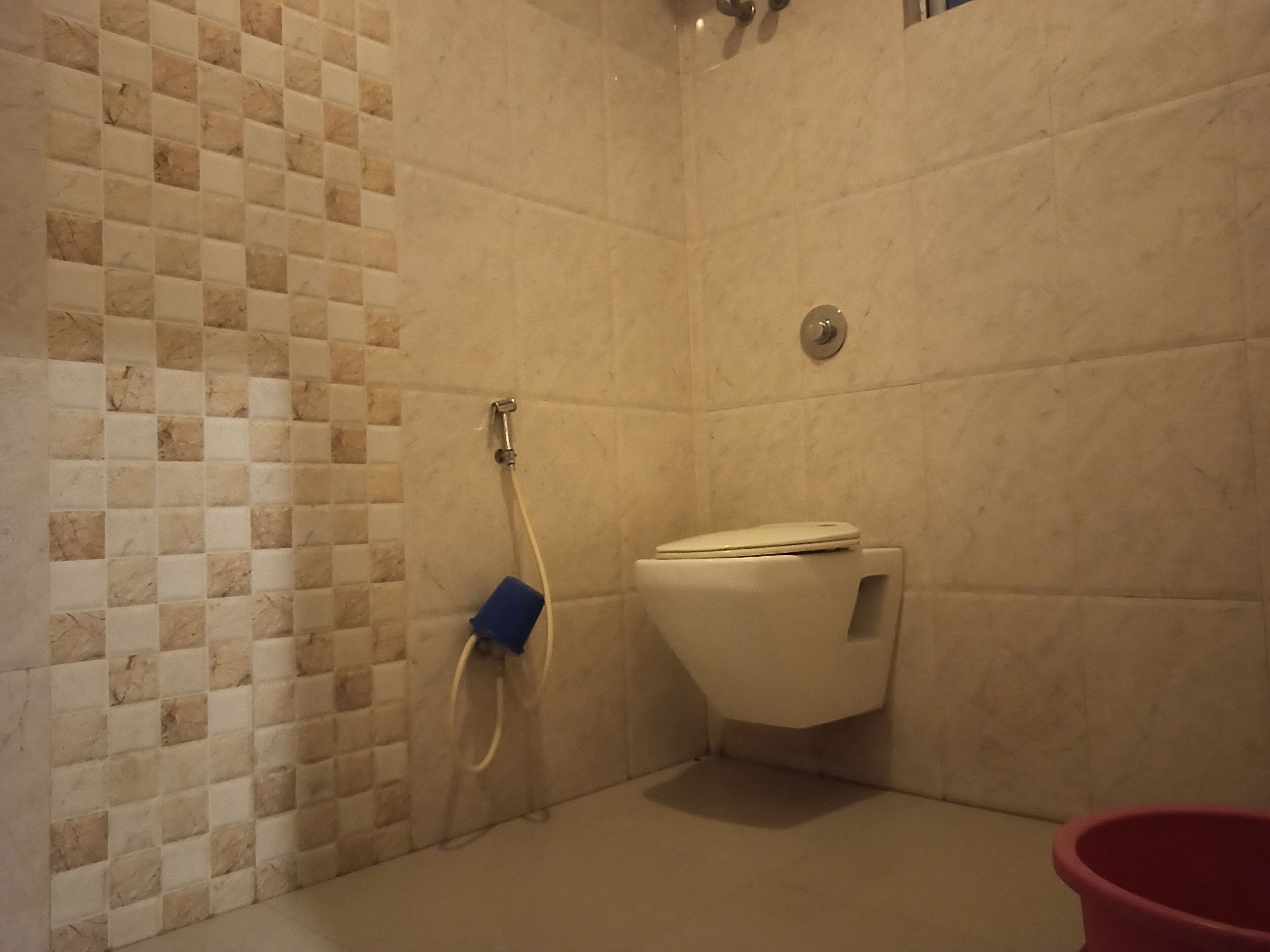 A bathroom with a tiled wall, a toilet, and a shower area.