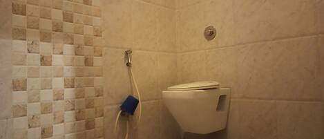 A bathroom with a tiled wall, a toilet, and a shower area.