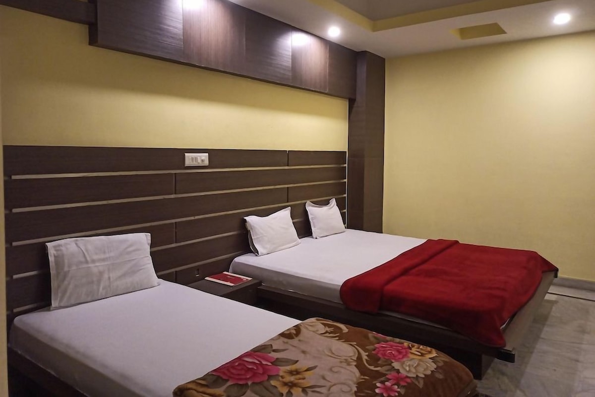 A hotel room with two beds, a wooden headboard, and a red throw blanket.