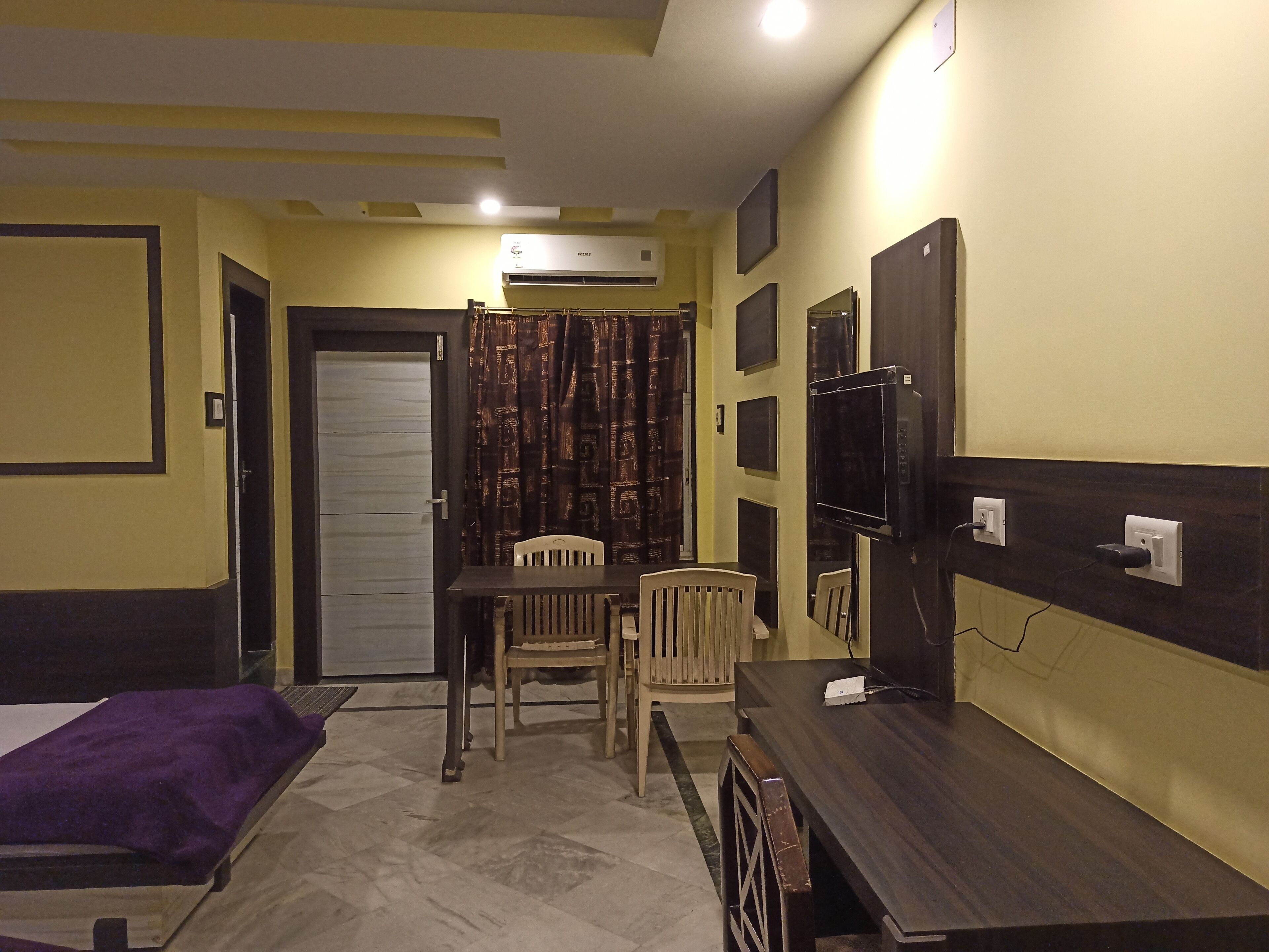 Une chambre d’hôtel équipée d’un lit, d’un bureau, d’une chaise, d’une télévision et d’un appareil de climatisation.