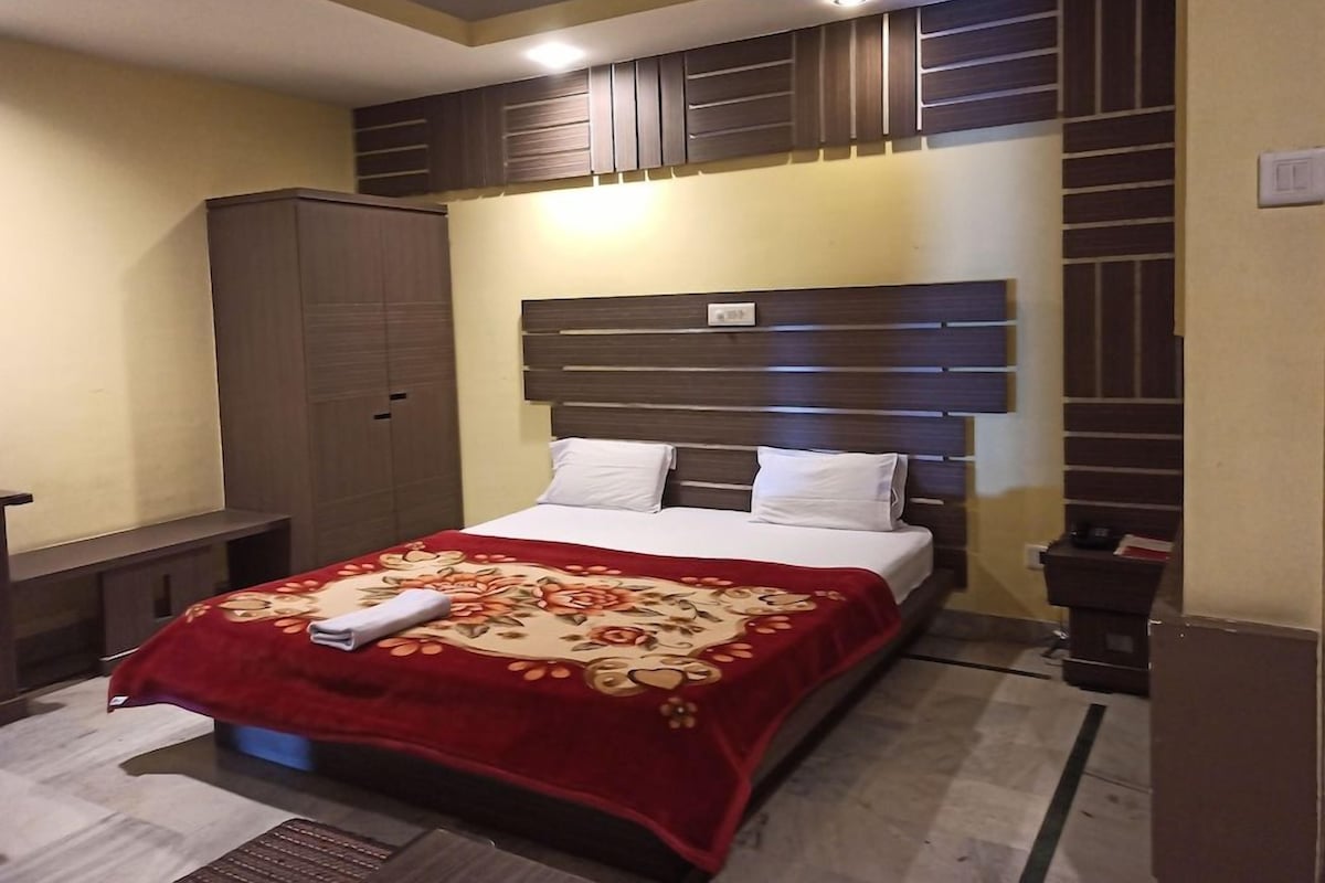 A hotel room with a bed, a wardrobe, a bedside table, and a wall-mounted heater.