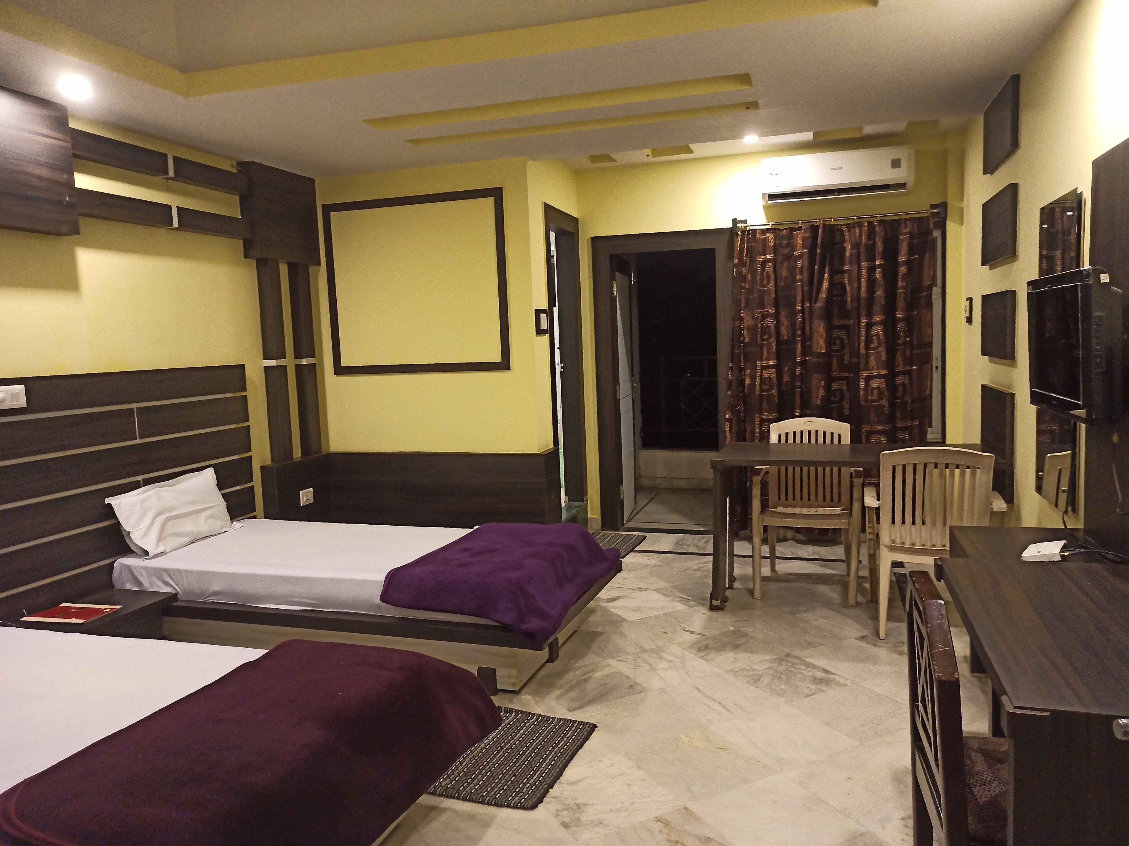 Une chambre d’hôtel avec deux lits, un bureau, une chaise et un téléviseur.
